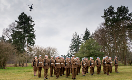 Boeing Apache helicopter flies over members of 4 Regiment, Army Air Corps at Markshall